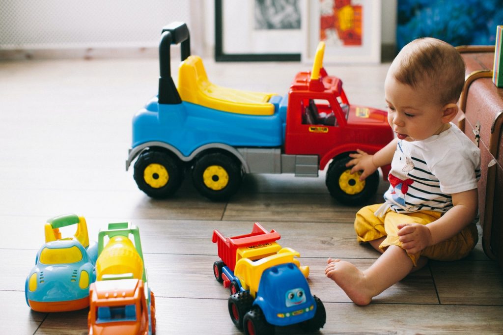 niemowlę i zabawkowe kolorowe samochodziki